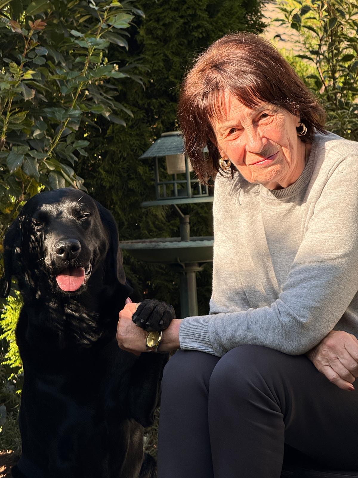 Roswitha, Verkaufsberaterin bei Pudelwohl365, mit ihrem Labrador Lou im Garten